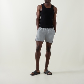Model wearing Hugo Boss Starfish Logo Swim Shorts in grey with contrast side piping, styled with a black vest and brown slides.