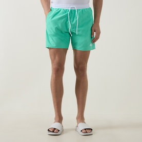 Model wearing Hugo Boss bright green swim shorts with white drawstring, styled with white slider sandals.