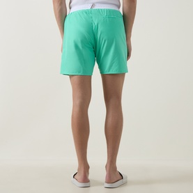 Model wearing Hugo Boss bright green swim shorts, rear view, styled with white slip-on shoes