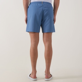 Model wearing Hugo Boss Swordfish Logo Swim Shorts in light pastel blue, rear view showing patch pocket and elasticated waistband, styled with white