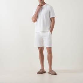 Model wearing Hugo Boss Structure Logo Textured Lounge Shorts in Natural, styled with a white T-shirt and taupe loafers.
