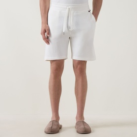 Model wearing Hugo Boss Structure Logo Textured Lounge Shorts in Natural, with drawstring waist and side pockets, styled with taupe loafers.