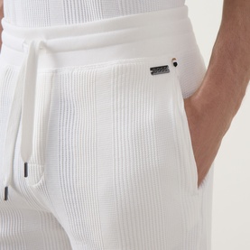 Model wearing Hugo Boss Structure Logo Textured Lounge Shorts in Natural, showing ribbed texture, drawstring waist and side pocket detail.
