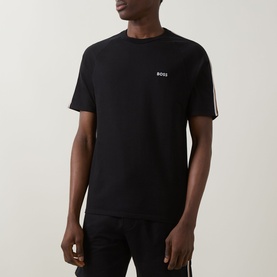 Model wearing Hugo Boss black cotton T-shirt with small chest logo and contrast stripe detail on sleeves, paired with dark trousers.