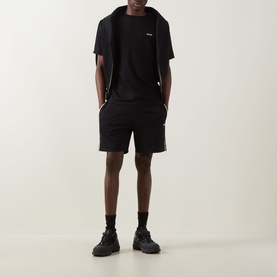 Model wearing Hugo Boss black cotton T-shirt styled with matching black shorts and black trainers.