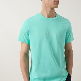 Model wearing Hugo Boss bright green cotton T-shirt with tonal embossed logo lettering across the chest