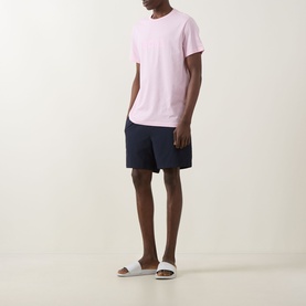 Model wearing Hugo Boss Big Logo T-Shirt in Bright Pink with navy shorts and white slider sandals