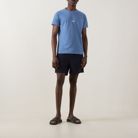 Model wearing Hugo Boss light blue T-shirt with small chest logo, styled with navy shorts and brown sandals