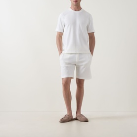 Model wearing Hugo Boss Structure Logo Textured Lounge T-Shirt in Natural, paired with white shorts and taupe loafers.