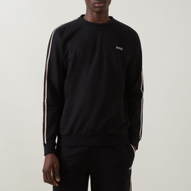 Model wearing Hugo Boss black cotton sweatshirt with contrast stripe sleeve detailing and small chest logo, styled with matching black joggers.