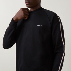 Model wearing Hugo Boss black cotton sweatshirt with white BOSS chest logo and contrast stripe detail on raglan sleeves.