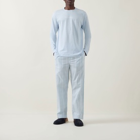 Model wearing Calvin Klein Logo Check Print Pyjama Set in ballad blue; long-sleeve top and check print straight-leg bottoms, styled with navy