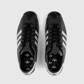 Adidas trainers in core black with silver metallic three stripes, white rubber sole, lace-up fastening, overhead flat-lay view