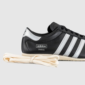 Adidas Paris trainer in core black with silver metallic three stripes, low-cut silhouette, cream rubber sole and spare laces