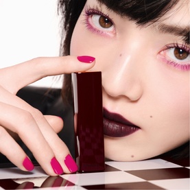 Model with CHANEL Rouge Allure Velvet Luminous Matte Lip Colour in deep berry, held to cheek, styled with pink nails and matching eye makeup