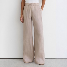 Model wearing Reiss beige wide-leg drawstring trousers with elasticated waistband, styled with a white top
