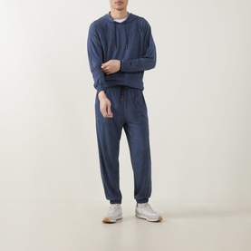 Model wearing Paul Smith Access Harry Lounge Sweatpants in blue, slim-leg with cuffed ankles, styled with matching blue sweatshirt and white trainers.