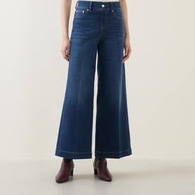 Model wearing Spanx E.W 2.0 Wide Leg Petite Jeans in Poseidon blue with wide-leg silhouette and front crease, styled with burgundy heeled boots.