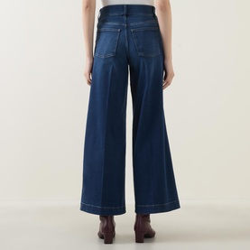 Model wearing Spanx E.W 2.0 Wide Leg Petite Jeans in Poseidon, back view showing wide leg silhouette and contrast stitching detail.
