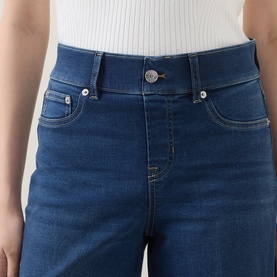 Model wearing Spanx E.W 2.0 Wide Leg Petite Jeans in Poseidon blue, close-up of button fastening and five-pocket detail, styled with white top.