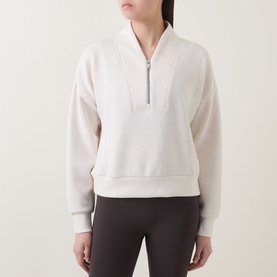 Model wearing Spanx Sweat Top in Oatmeal Heather, half-zip neckline, styled with dark grey leggings.