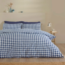 Catherine Lansfield Bamford Gingham Duvet Set in navy blue, styled on a double bed with two pillowcases, beside a wooden bedside table