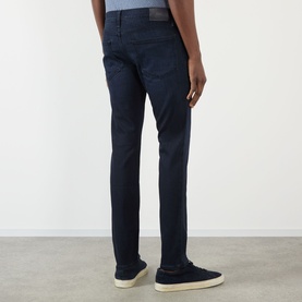 Model wearing Paige Lennox Slim-Leg Jeans in Hastings dark-wash denim, rear view, styled with white trainers.