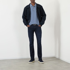 Model wearing Paige Lennox Slim-Leg Jeans in Hastings dark wash, styled with navy bomber jacket, blue polo and navy trainers.