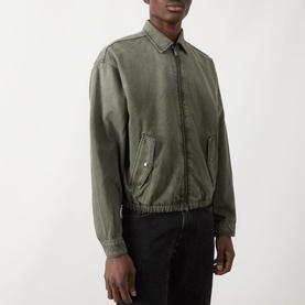 Model wearing Seven Jeans Casual Jacket in Sunfaded Moss, cotton-lyocell bomber style with flap pockets and elasticated hem, styled with black jeans.