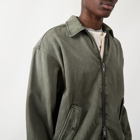 Model wearing Seven Jeans Casual Jacket in Sunfaded Moss, zip-front with spread collar and patch pockets, styled over white tee.