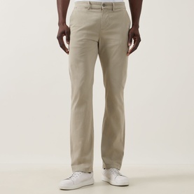 Model wearing Seven Jeans Slimmy Stretch Slim Leg Jeans in Rawhide, styled with white trainers. Five-pocket chino with fly zip fastening.