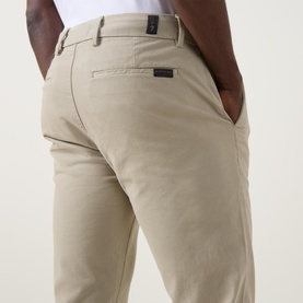 Model wearing Seven Jeans Slimmy Stretch Slim Leg Jeans in Rawhide, showing rear pocket detail with branded tab and belt loops.