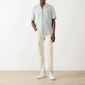 Model wearing Seven Jeans Dusty Blue lyocell reg shirt with cream trousers and white trainers.