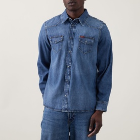 Model wearing Seven Jeans Western Denim Shirt in Canyon mid wash, featuring point collar, snap placket, dual chest pockets and tobacco stitching