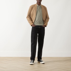 Model wearing Seven Jeans Army Regular Polo, styled with a tan bomber jacket, black jeans and black canvas trainers.