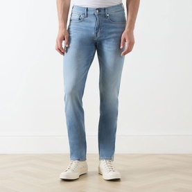Model wearing Seven Jeans 3049 Slim Jeans in Haven light blue wash, styled with white trainers.
