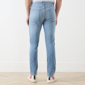 Model wearing Seven Jeans 3049 Slim Jeans in Haven light blue wash, rear view, styled with white trainers
