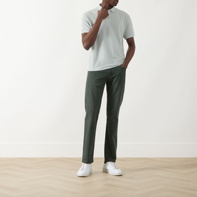 Model wearing Seven Jeans Dusty Blue Regular Polo in lyocell-cotton blend, styled with dark green trousers and white trainers.
