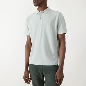 Model wearing Seven Jeans Dusty Blue Regular Polo in short-sleeve piqu&eacute;, styled with dark green trousers.