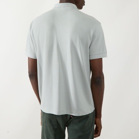 Model wearing Seven Jeans Dusty Blue Regular Polo, rear view, short sleeves, ribbed collar, styled with khaki trousers.