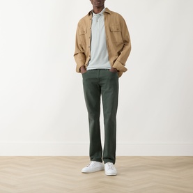 Model wearing Seven Jeans Dusty Blue Regular Polo, styled with a tan overshirt, dark green trousers, and white trainers.