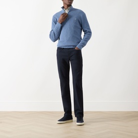 Model wearing Seven Jeans Ultramarine slim jeans, styled with a blue quarter-zip knit and navy trainers