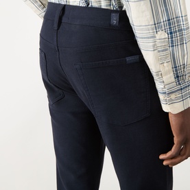 Model wearing Seven Jeans Slim 3049 ultramarine jeans, rear view showing back pockets, styled with a blue plaid shirt.