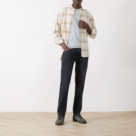 Model wearing Seven Jeans Slimmy Slim Leg Jeans in Breakwater, dark indigo wash, styled with a cream check shirt and light blue tee