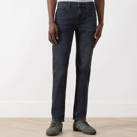 Model wearing Seven Jeans Slimmy Slim Leg Jeans in Breakwater, dark washed denim with subtle fading, styled with grey Adidas trainers.