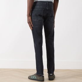 Model wearing Seven Jeans Slimmy Slim Leg Jeans in Breakwater, rear view showing logo badge, faded details and slim fit, styled with grey trainers.