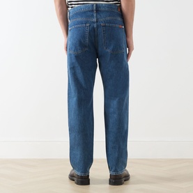 Model wearing Seven Jeans 3049 Straight Jeans in Kingfisher blue denim, rear view, styled with black leather shoes