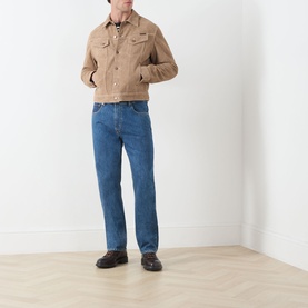 Model wearing Seven Jeans Kingfisher straight jeans styled with a tan trucker jacket and dark loafers.