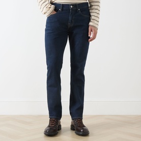 Model wearing Seven Jeans Sundown straight jeans in dark indigo wash, styled with a striped knit and brown lace-up boots.
