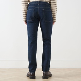 Model wearing Seven Jeans Sundown straight jeans in dark indigo, rear view, styled with a striped top and dark leather shoes.